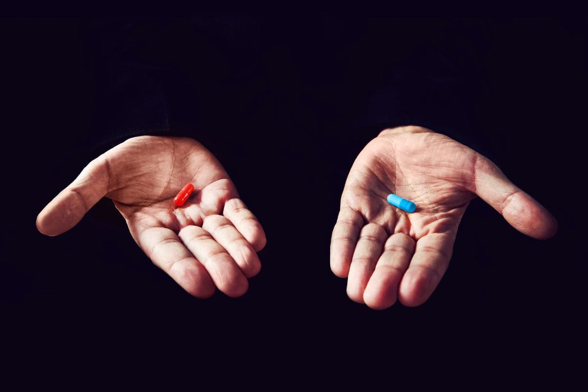 Duas mãos abertas segurando pílulas vermelha e azul representando escolhas financeiras e como emoções influenciam decisões sobre dinheiro